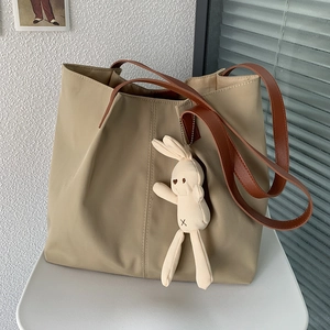 Close-up of khaki nylon tote bag with brown straps and a cute knit bunny pendant