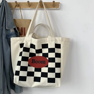 Close-up of beige canvas tote bag featuring a black and white checkerboard Boom print
