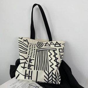 Artistic detail of canvas tote bag featuring black abstract patterns and sturdy straps
