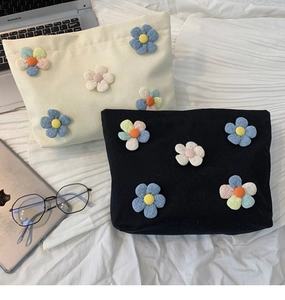 Detail of canvas makeup bags featuring 3D floral patches on cream and black fabric