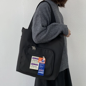 Detail der schwarzen Nylon-Einkaufstasche mit Reißverschlusstasche und Aufnäher am Model