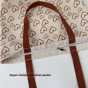 Detail view of canvas tote bag zipper closure with red heart patterns and inner pocket