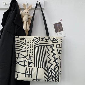 Detailed close-up of a cream canvas tote bag featuring black abstract geometric patterns