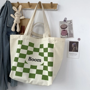 Detail of canvas tote bag with green checkerboard pattern and Boom lettering detail