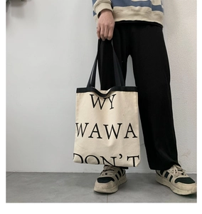 Detail of minimalist canvas tote bag featuring black letter print and sturdy top handles