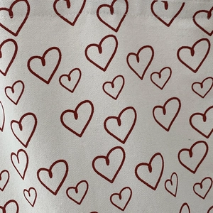 Close-up of red heart print on durable beige canvas fabric with woven texture