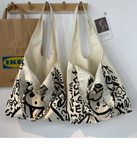 Detail of white canvas tote bags with black graffiti patterns hanging on wooden hooks