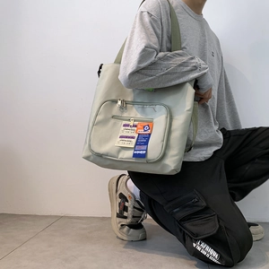 Detail der graugrünen Canvas-Umhängetasche mit Doppeltaschen und Vintage-Patch-Labels