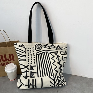 Detail of canvas tote bag showing black geometric pattern and durable shoulder straps