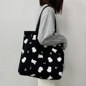 Détail du fourre-tout en toile noire avec motifs de chiots blancs et notes de musique