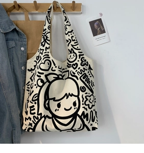 Detail of canvas tote bag with black cartoon doodle illustration on a wall hook