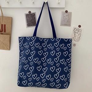 Close-up of navy canvas tote bag featuring white heart print and reinforced handles