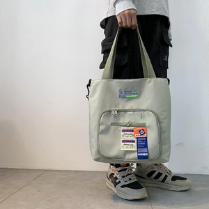 Detail der hellgrünen Canvas-Tasche mit Reißverschlusstasche und Industrie-Label