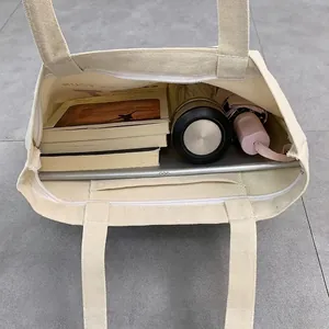 Large beige canvas tote bag showing spacious interior with tablet, books, and bottle