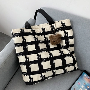 Detail of large canvas tote bag with black and white grid and plush bear charm