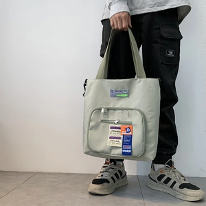 Detailansicht der hellgrünen Nylon-Tragetasche mit Industrie-Patches und Reißverschlusstasche