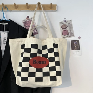 Detail of beige canvas tote bag with black and white checkerboard and red Boom logo