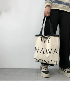 Detail shot of a large canvas tote bag with WY WAWA letters and black handle trim