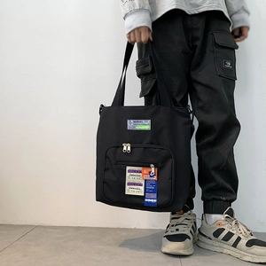Detail der schwarzen Nylon-Tasche mit industriellem Warnaufnäher und Streetstyle-Design