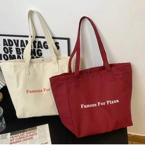 Détail de la fermeture à bouton et des lettres vintage sur les sacs en toile
