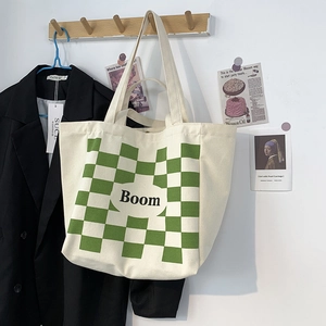 Detail of canvas tote bag with green checkerboard pattern and Boom logo hanging on hook