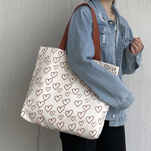 Detail of white canvas tote bag with red heart pattern and small matching zipper pouch