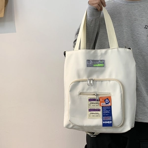 Detail der cremeweißen Nylon-Tote-Bag mit taktischen Taschen und stylischem Patch-Stick