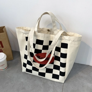 Detail of canvas tote bag showing checkerboard pattern with Boom text and snap button