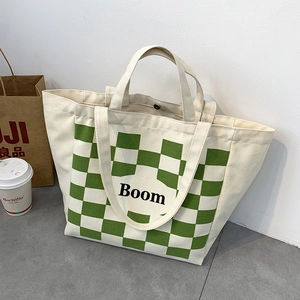 Detail of canvas tote bag featuring green checkerboard pattern and Boom lettering print