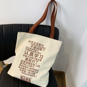 Detail of off-white canvas tote bag with brown straps and Chinese motivational slogans