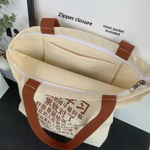 Detail of canvas tote bag showing top zipper closure and internal storage pocket