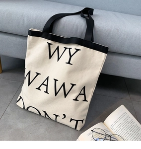 Close-up of minimalist canvas tote bag with black letter print on a sofa in a cozy setting