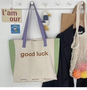 Detail of color-block canvas tote bag featuring magnetic closure and printed lettering
