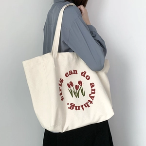 Cream canvas tote bag with red tulips and girls can do anything slogan shown on model