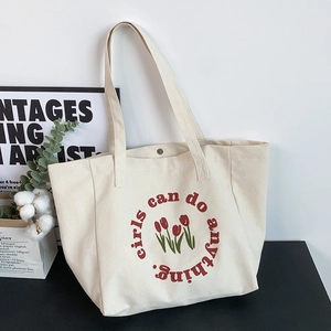 Close-up of beige canvas tote bag featuring red tulip print and magnetic metal closure