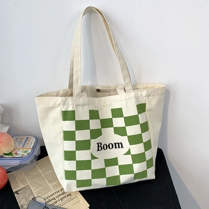Detail shot of large canvas tote bag with green checkerboard pattern and Boom lettering