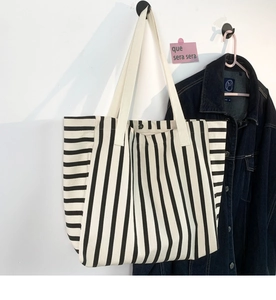 Detail of striped canvas tote bag showing reinforced strap and button closure