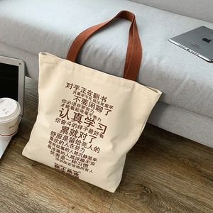 Detail of a thick canvas tote bag with brown straps and inspirational Chinese print