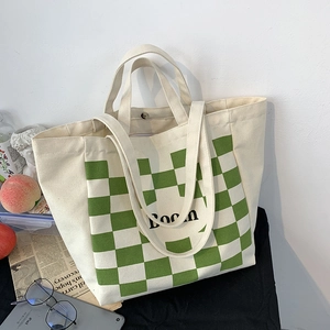 Detail of a large canvas tote with green checkered pattern and Boon lettering on a table