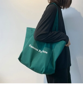 Détail du sac cabas en toile vert foncé avec texte Famous For Pizza blanc et bandoulière