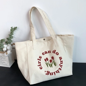 Detail of canvas tote bag with red tulips and 'girls can do anything' slogan