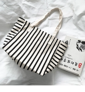Detailed top view of striped canvas tote bag on white fabric background with book