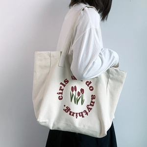 Close-up of a white canvas tote bag with red tulip print and girls can do anything text
