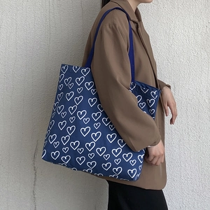Detail view of navy blue canvas tote bag featuring white hand-drawn heart print patterns