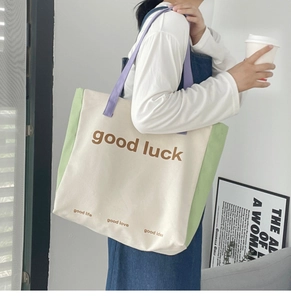 Close-up of color-block canvas tote bag with good luck print and green trim detail