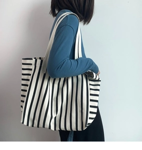 Detail of large black and white striped canvas tote bag showing texture and shoulder strap