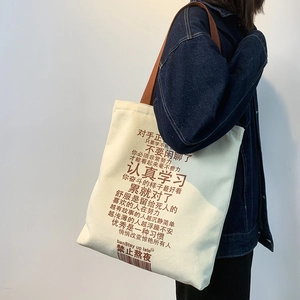 Detail of off-white canvas tote bag with black Chinese text and brown strap straps