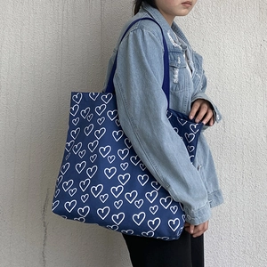 Close-up of large blue canvas tote bag with white heart patterns and matching inner pouch