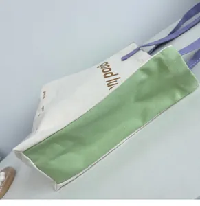 Detail view of canvas tote side panel with green fabric and 'good luck' print