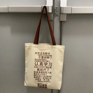 Macro detail of canvas tote bag showing inspirational Chinese text and brown strap